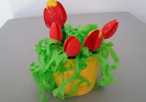 Wazon z tulipanami wykonany przy użyciu pojemnika po jogurcie, plastikowych łyżeczek, zielonej i żółtej bibuły, czerwonej farby.