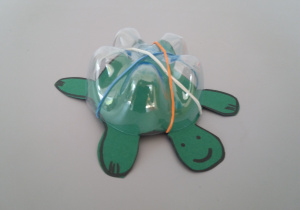Żółw wykonany przy użyciu dna plastikowej butelki, ilustracji żółwia wyciętego z kartonu i gumek recepturek.