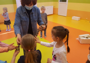 Dzieci z grupy VI dotykają węża trzymanego przez edukatora.