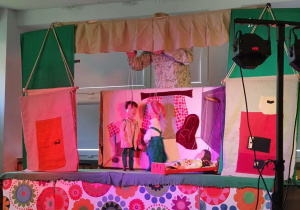 Aktor porusza marionetkami na scenie.