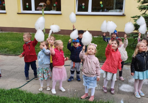 Dzieci z grupy I z watą cukrową w ogrodzie przedszkolnym.