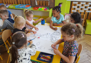 Dzieci z grupy VI zamalowują wspólnie kontury dużej kolorowanki.