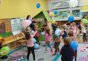 Dzieci i nauczyciel z grupy III podczas zabawy z balonami