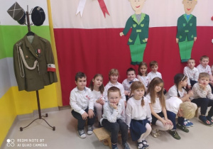 Dzieci siedzą przy stroju żołnierza.
