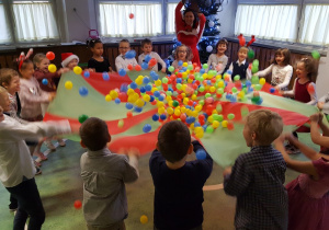Dzieci z grupy VI podczas zabaw z użyciem chusty animacyjnej i kolorowych piłeczek